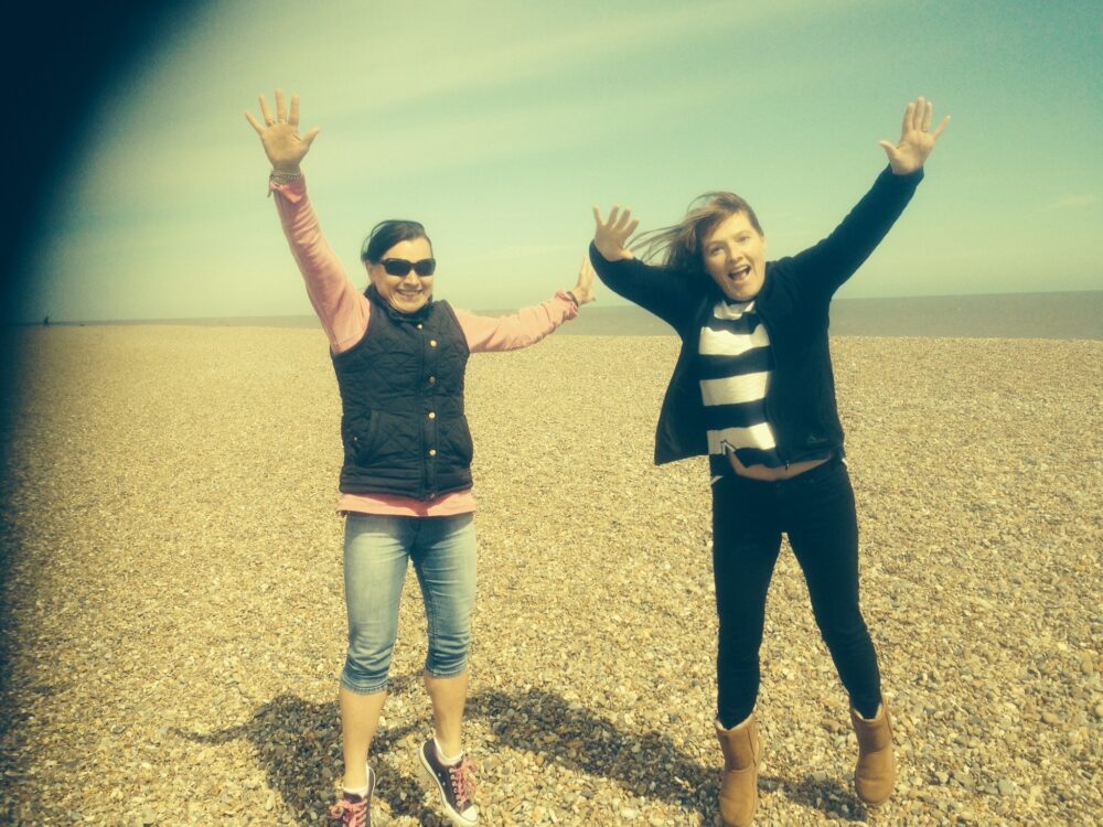 Two women jumping for fun on a beach.