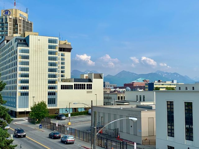 Downtown view of Anchorage with high rise hotels and mountains in the distance.
