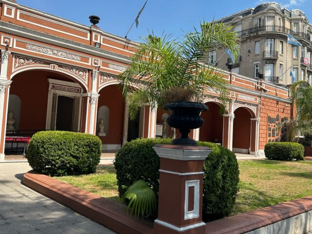 Mueso Nationale Historica is a red brick building with shrubs and trees in the front of it. It houses many of the important historical artifacts of Argentina.