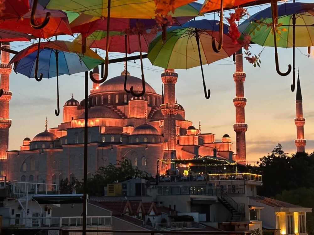 Nightime sunset view of Hagia Sofia Istanbul from rooftop shaded by multicolored umbrellas. Rooftops are a great way to get a Birds Eye view of Istanbul as a first-timers.