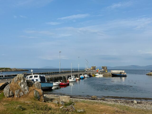 Views of an island harbour and ferry port on the isle of Colonsay Scotland. Small local boats are tied up along the stone harbor walls.