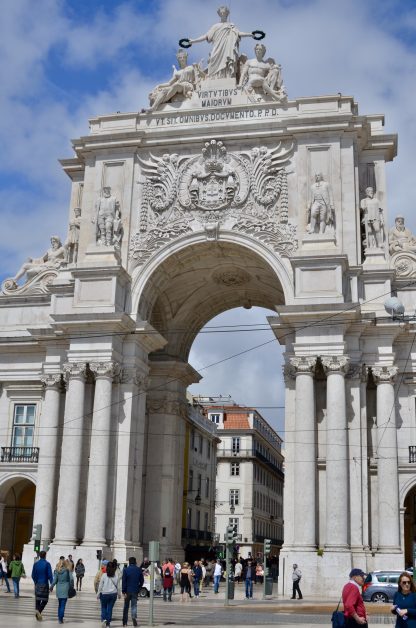 A massive stone archway with 3 columns flanking each side and on top multiple statues.