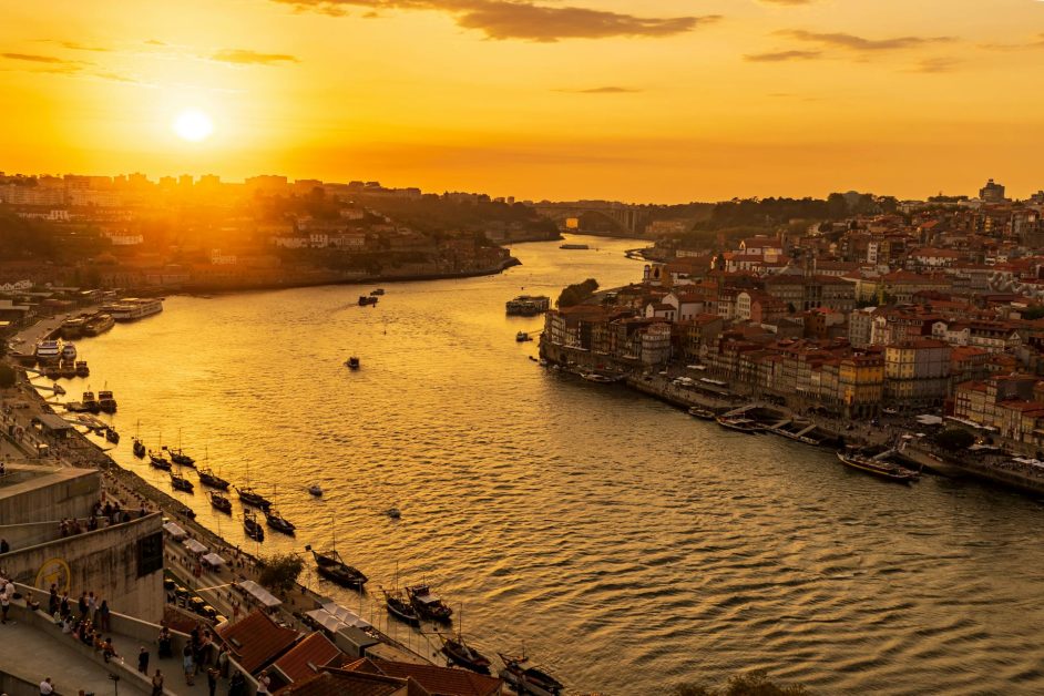 A sunset view over the River Douro with a row of small fishing boats tied up for the night.