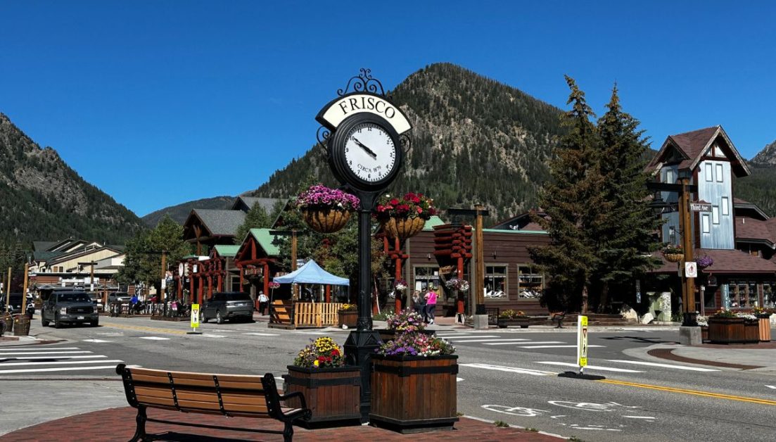A view of the town clock and main street of Frisco Colorado. Flower tubs line the street.