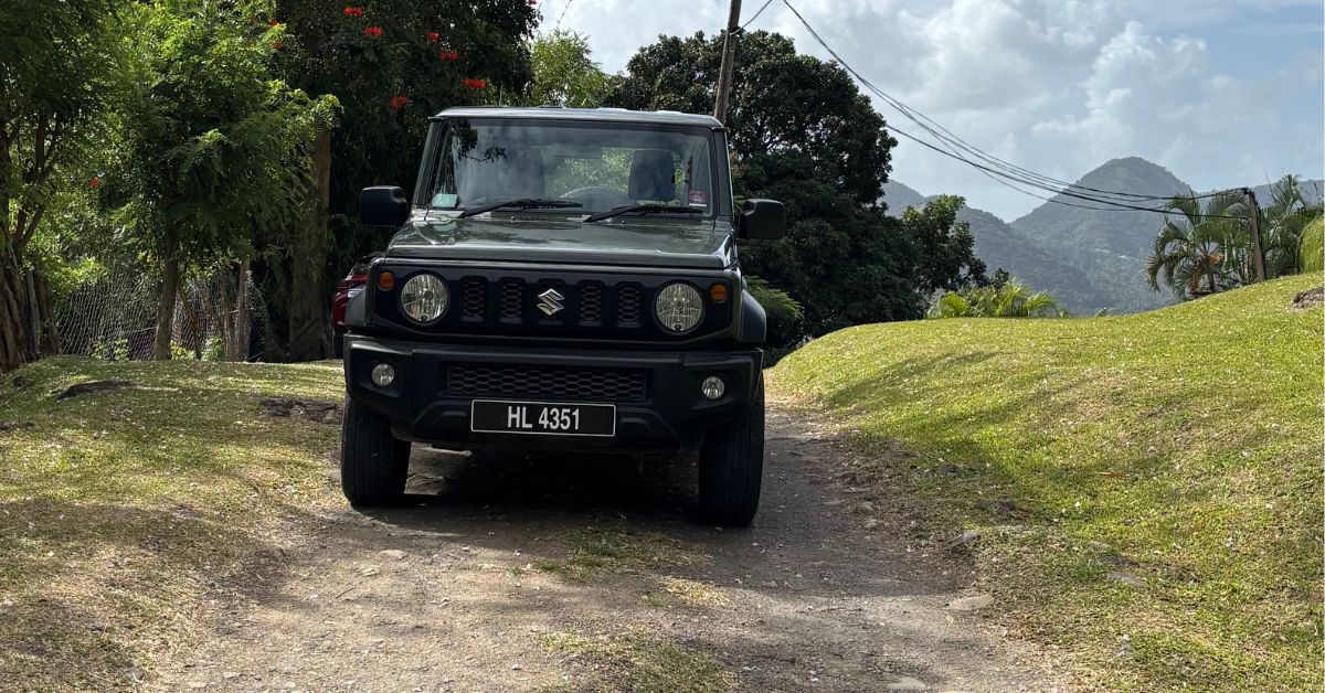 Jeep Parked up on a track road which is unpaved. Hills in the background. Grassy banks either side of the vehicle.