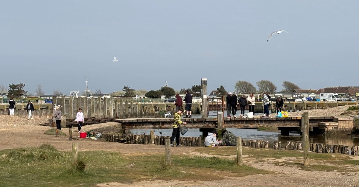 People standing on a wooden bridge with crabbing nets